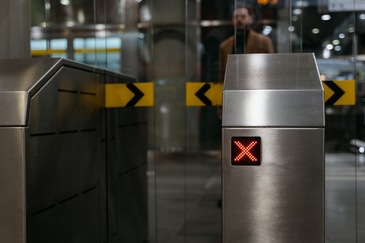 Close-up of a stainless steel ticket barrier with red X signal indicating no entry.